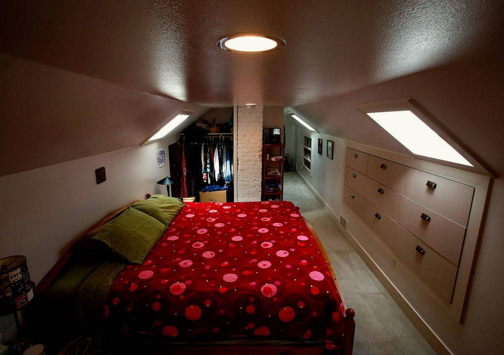A cozy bedroom, bath and office in the finished attic boasts built-in shelving, drawers and skylights.