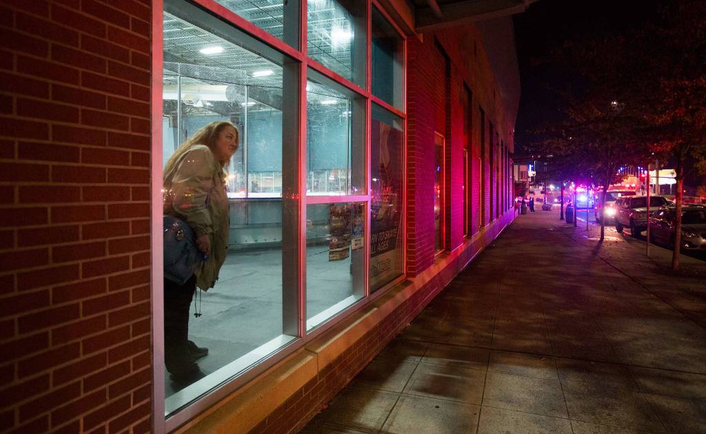 A woman watches from Xfinity Arena as firefighters pour water on Mondays fire at Everett Office Furniture on Broadway. (Andy Bronson / The Herald)