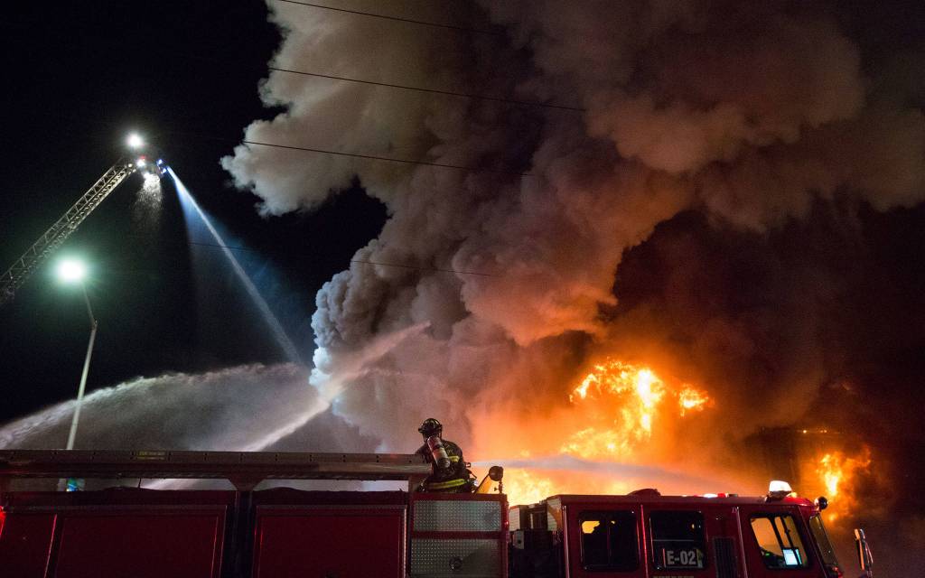 Firefighters pour water on Mondays fire at Everett Office Furniture on Broadway. (Andy Bronson / The Herald)