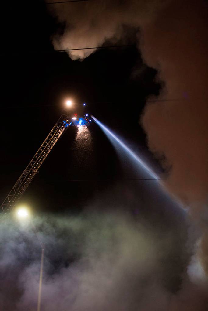 Firefighters pour water on a three-alarm fire at Everett Office Furniture on Broadway on Monday in Everett. (Andy Bronson / The Herald)