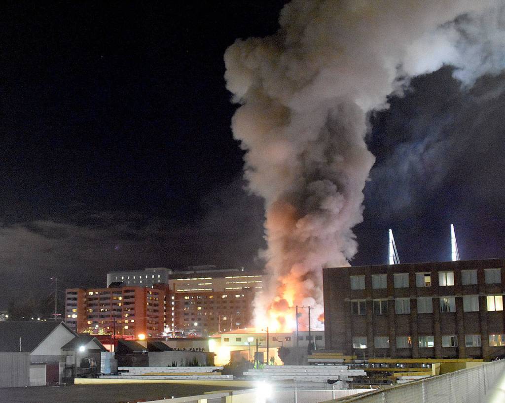 A massive fire at a furniture store filled downtown Everett with smoke Monday night. Firefighters rescued a man from a neighboring apartment building. (Caleb Hutton / The Herald)