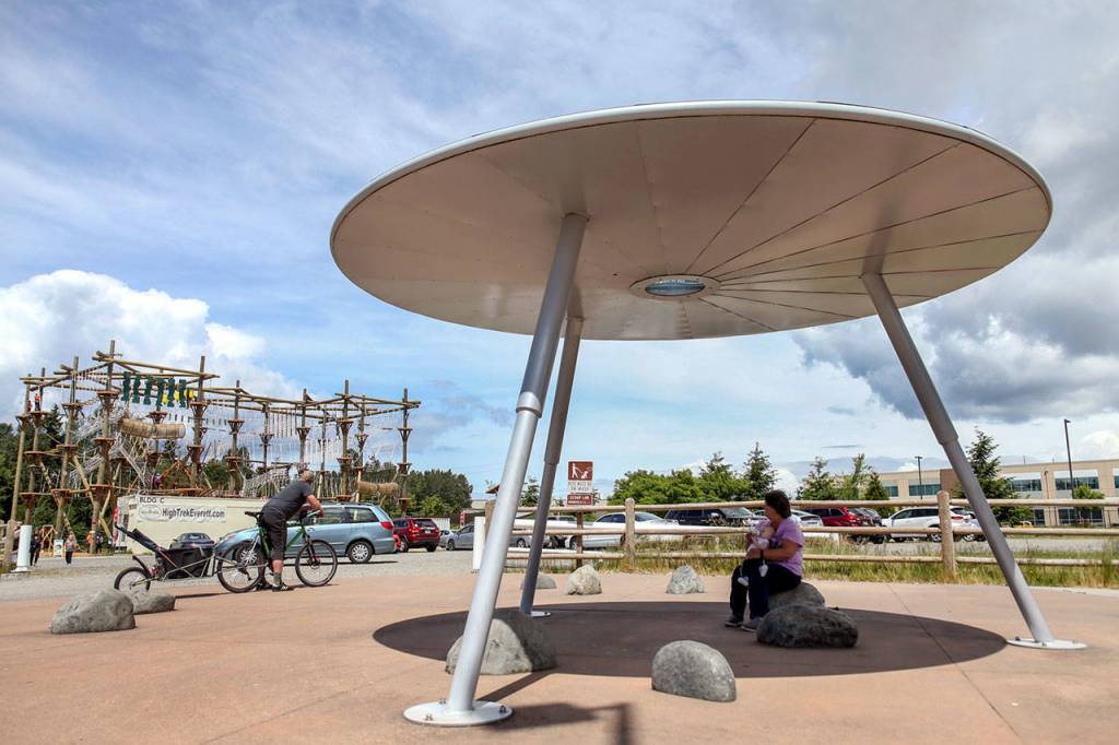 Juli Siegel rests in the shadow of the giant UFO-style sculpture at the Paine Field Community Park playground. (Kevin Clark / The Herald)