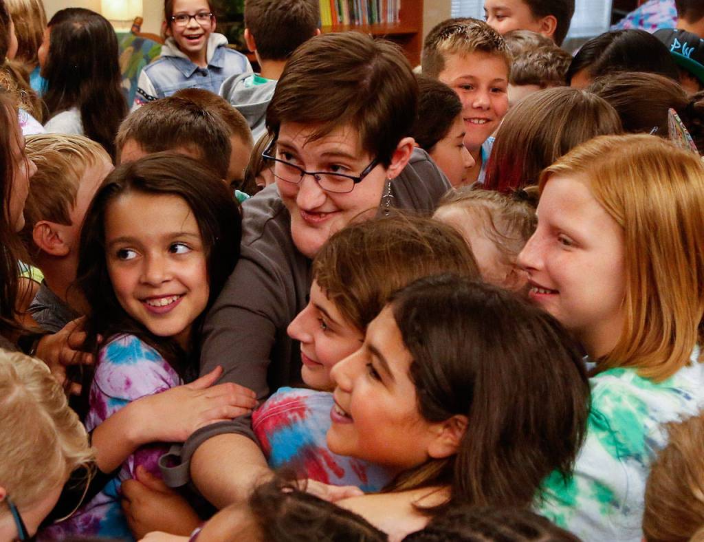 Abby Beauchamp, who was born with a facial abnormality, is surrounded and hugged by the students. (Dan Bates / The Herald)