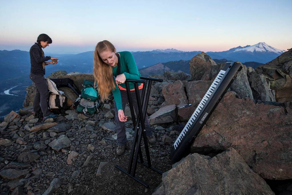Rose Freeman (center) and Anastasia Allison prepare their instruments at sunrise at the summit. (Ian Terry / The Herald)