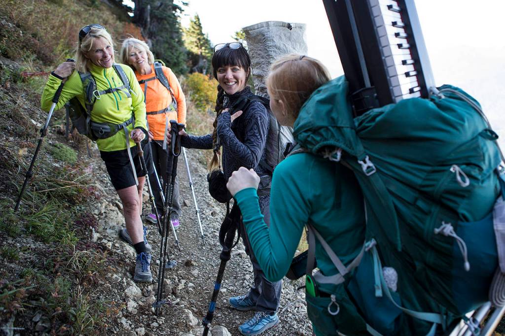 Katie Carpenter (left) and her friend Ann Willson (center left) stop to chat with Anastasia Allison and Rose Freeman as the musicians make their way back down Sauk Mountain after playing there. (Ian Terry / The Herald)