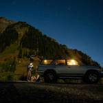 Anastasia Allison prepares her bag under a starry night before ascending Sauk Mountain, seen in the distance, with Rose Freeman to play music at sunrise on Oct. 5. (Ian Terry / The Herald)