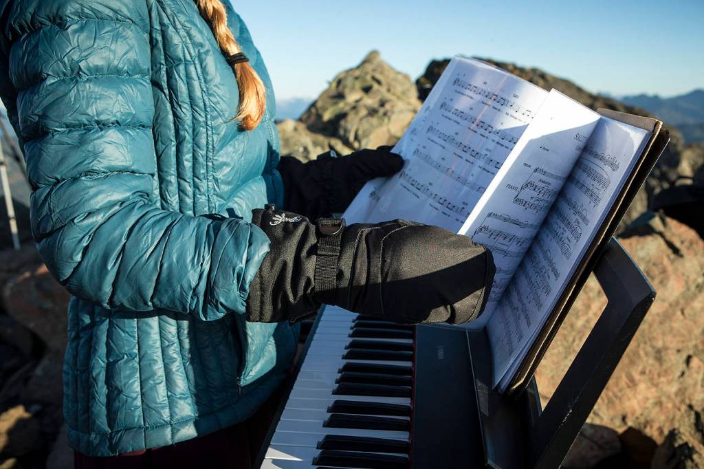 Rose Freeman flips through her sheet music with mittens to keep her hands warm before playing with friend Anastasia Allison atop Sauk Mountain on Oct. 5. (Ian Terry / The Herald)