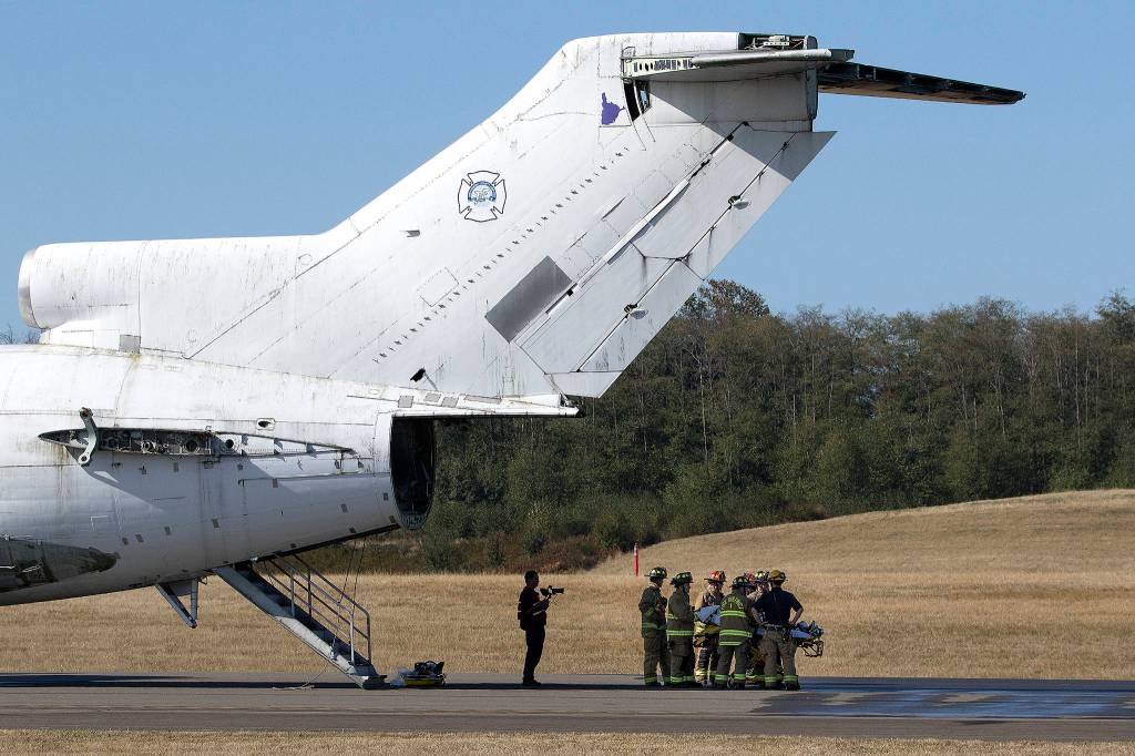 Firefighters wait to load one of 60 passengers, played by Grantie Falls drama students, onto an awaiting helicopter during a airplane casualty drill at Paine Feild on Sept. 26 in Everett. (Andy Bronson / The Herald)
