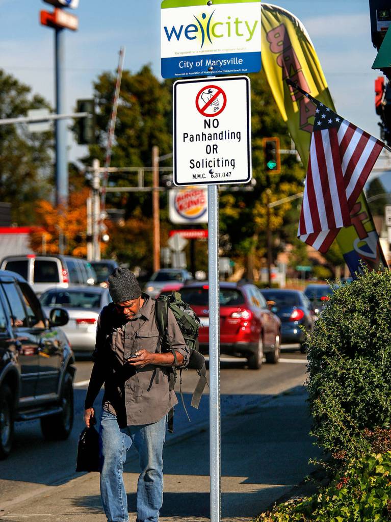 Houston passes beneath new Marysville signage as he walks toward I-5 along Fourth Street earlier this week. (Dan Bates / The Herald)