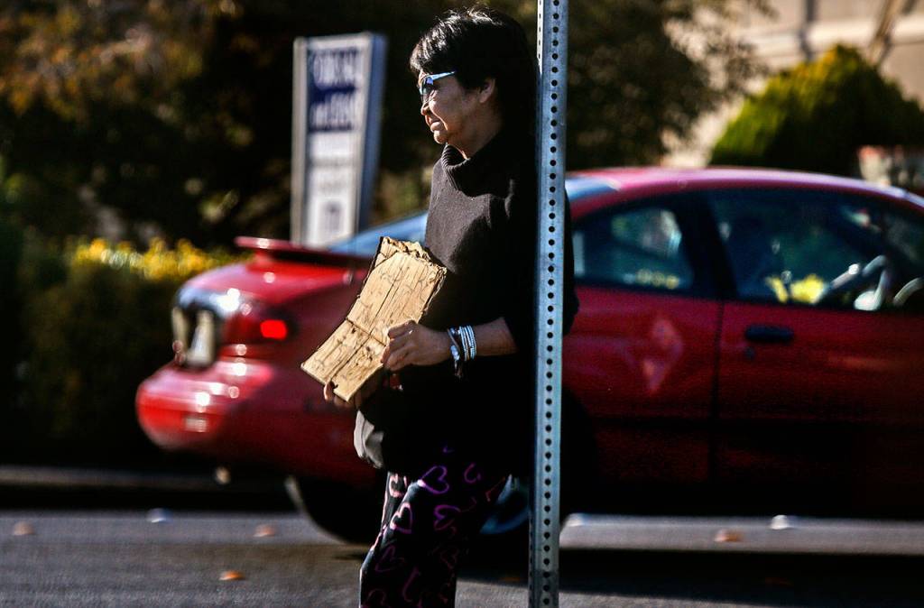 A woman named Mary, who said she is a 65-year-old widow, holds a sign asking for help near a parking lot on State Avenue in Marysville on Wednesday. In a half-hour, she said, she had been given 25 cents. (Dan Bates / The Herald)