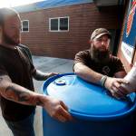 Matt Cash (left) and Taylor Pesce work to install a rain barrel at Experience Momentum in Lynnwood on Oct. 11. Cash and Pesce work along with other veterans in a group that completes projects around the county for the Snohomish Conservation District. (Ian Terry / The Herald)