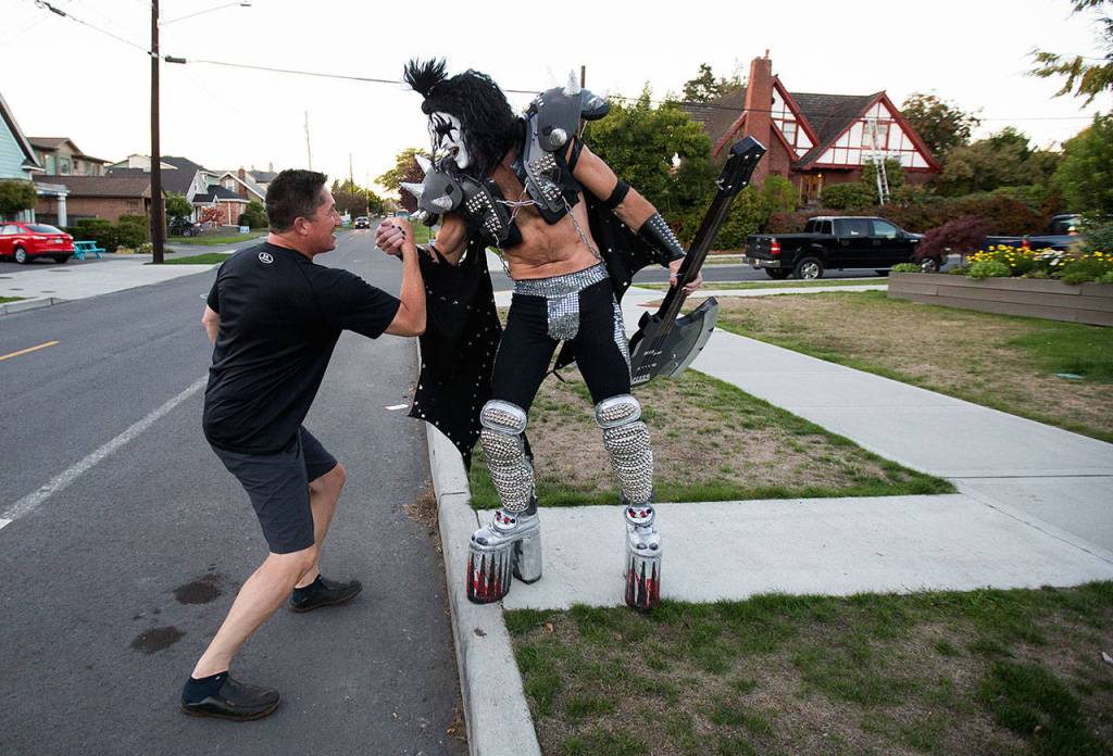 Dressed up as Gene Simmons of KISS fame, Everett paramedic Jack Murrin and neighbor John Tanaka greet each other out on the street as Murrin heads out to a open mic session at Cafe Zippy on Oct. 7 in Everett. (Andy Bronson / The Herald)