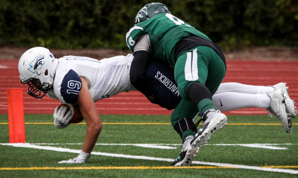 Meadowdales Will Moloney (left) dives into the end zone for a touchdown as Edmonds-Woodways Dominic Lawrence defends during a game Oct. 6, 2017, at Edmonds Stadium. (Ian Terry / The Herald)