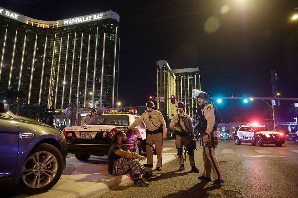 In this Sunday, Oct. 1, 2017 file photo, police officers stand at the scene of a mass shooting near the Mandalay Bay resort and casino on the Las Vegas Strip, in Las Vegas. (AP Photo/John Locher, File)