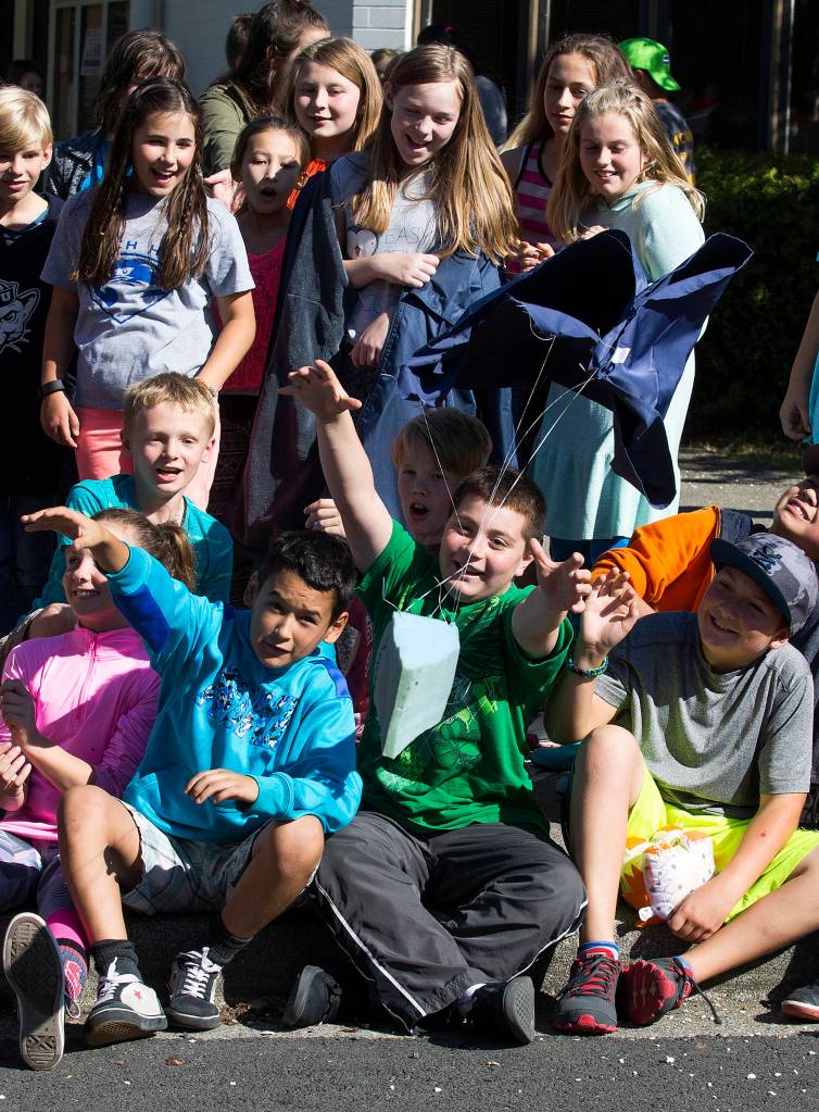 Dutch Hill Elementary fifth and sixth graders reach out to catch a parachute-rigged egg as they watch their landing crafts protect raw eggs survive  or not  a 70-foot drop from the top of a ladder truck on Oct. 5 in Snohomish. (Andy Bronson / The Herald)