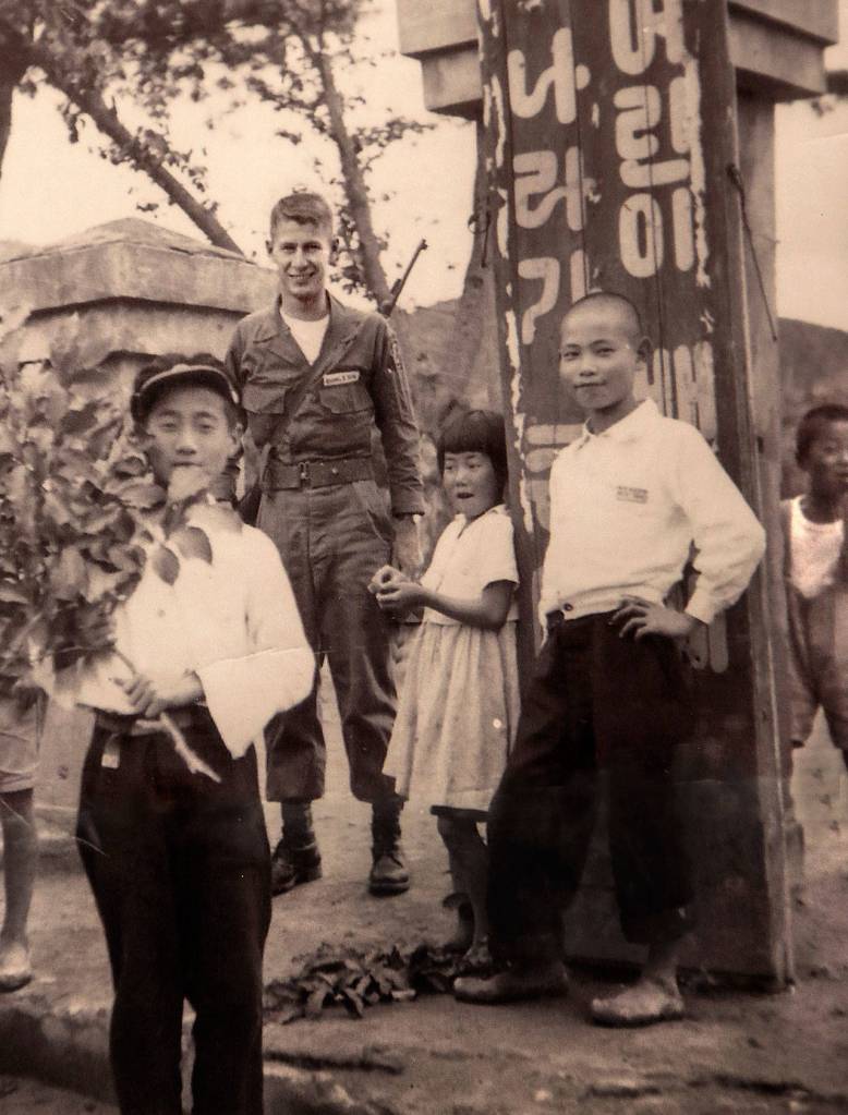 When the fighting stopped a month or so after Gerald Rogers got to the Korean War, he stayed on another year. Here, he was photographed with local children.