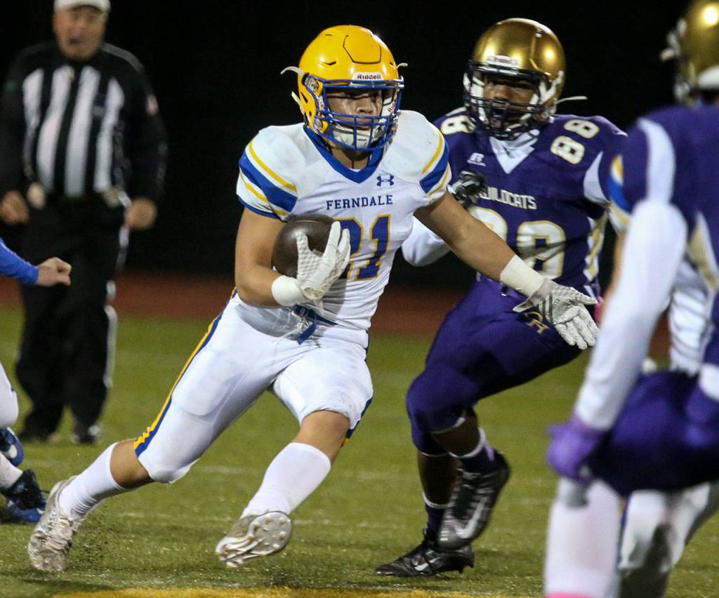 Ferndales Cole Semu (left) carries the ball with Oak Harbors Devon Morris trailing during a game Oct. 13, 2017, at Oak Harbor High School. (Kevin Clark / The Herald)