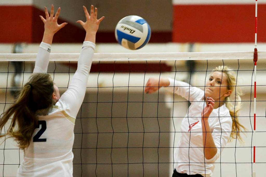 Stanwoods Devon Martinka (right) spikes a ball past Arlingtons Caroline Diemer during Tuesdays match at Stanwood High School. (Ian Terry / The Herald)
