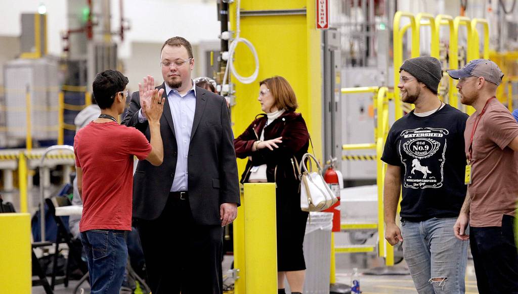 Spar assembly robotics cell operator Sam Martinez (left) high-fives equipment and tooling manager V.J. Bolton after Martinez started the machine to place the first fastener in a wing spar for a Boeing 777X jetliner in a ceremony marking the beginning of production of the jetliner on Monday in Everett. (AP Photo/Elaine Thompson)