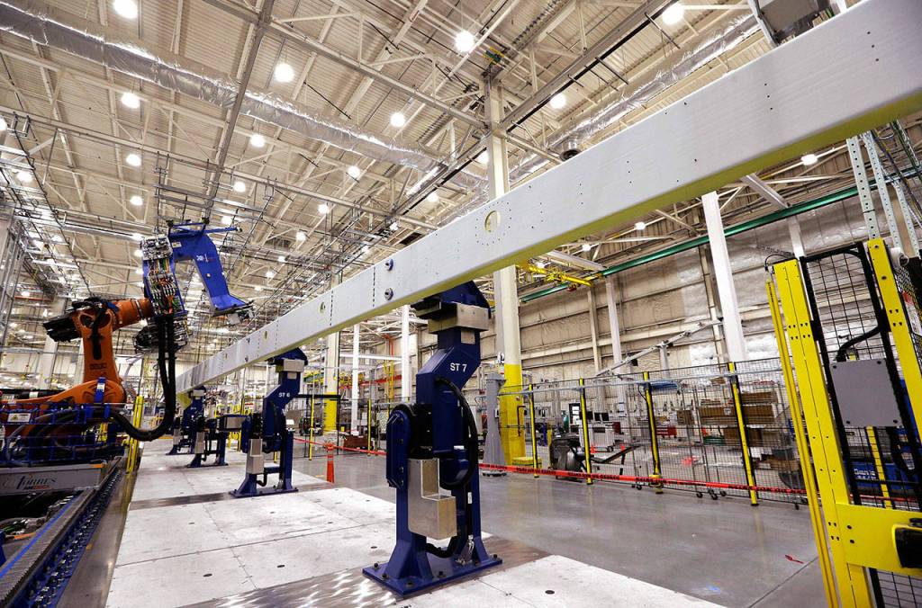 A wing spar for a Boeing 777X jetliner stands supported in a spar assembly robotics cell, with the machine that will drill holes and insert fasteners at left, Monday in Everett. (AP Photo/Elaine Thompson)