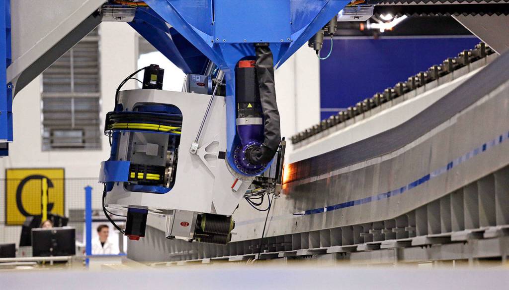 A Boeing worker stands at the back of an automated fiber placement machine as carbon fiber is laid down to create a massive wing for the Boeing 777X in Everett. (AP Photo/Elaine Thompson)