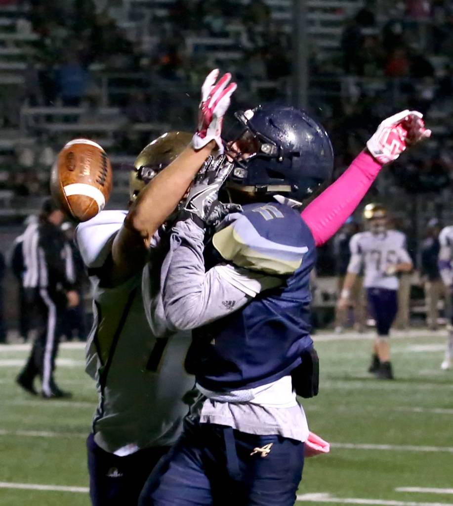 Oak Harbors Kyle Nickols breaks up a pass in the end zone intended for Arlingtons Cambell Hudson during a game Oct. 20, 2017, at Arlington High School. (Kevin Clark / The Herald)