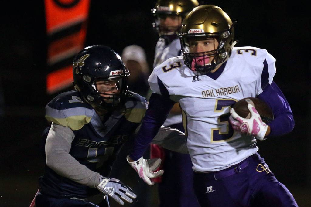 Oak Harbors Andrew Miller scrambles with Arlingtons Jacob Hubbard giving chase during a game Oct. 20, 2017, at Arlington High School. (Kevin Clark / The Herald)