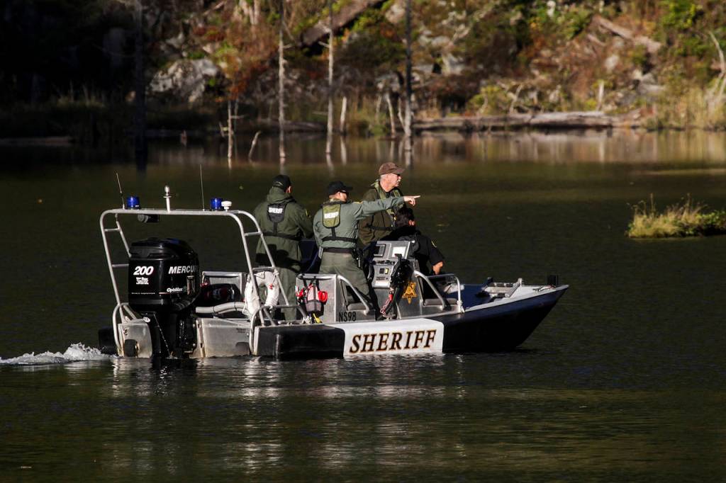 Investigators make their way across King Lake near the site of a helicopter crash Tuesday. (Ian Terry / The Herald)