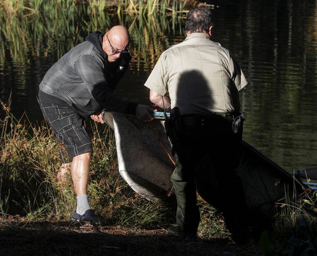 Jeffrey Abrams (left) pulls his dinghy ashore from King Lake on Tuesday. (Ian Terry / The Herald)