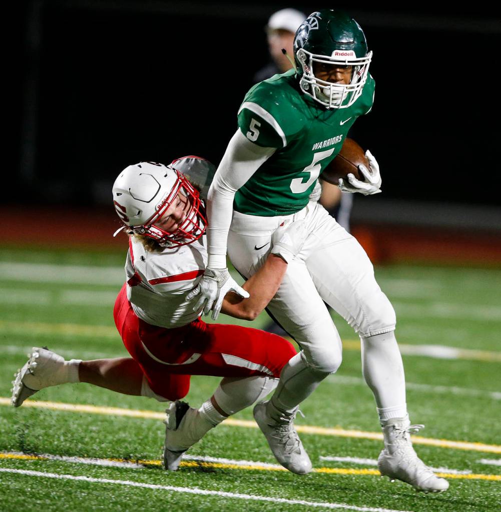Edmonds-Woodways Aaron Richardson (right) breaks a tackle during the Warriors 38-17 win over Snohomish on Friday at Edmonds Stadium. (Ian Terry / The Herald)
