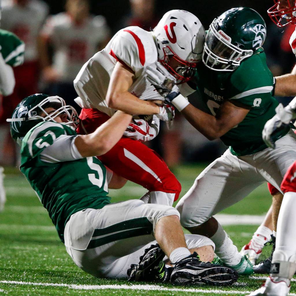 Snohomishs Tyler Massena (center) is brought down by Edmonds-Woodways Tyler McAtee (left) and Dominic Lawrence (right) during the Warriors 38-17 win over the Panthers on Friday at Edmonds Stadium. (Ian Terry / The Herald)