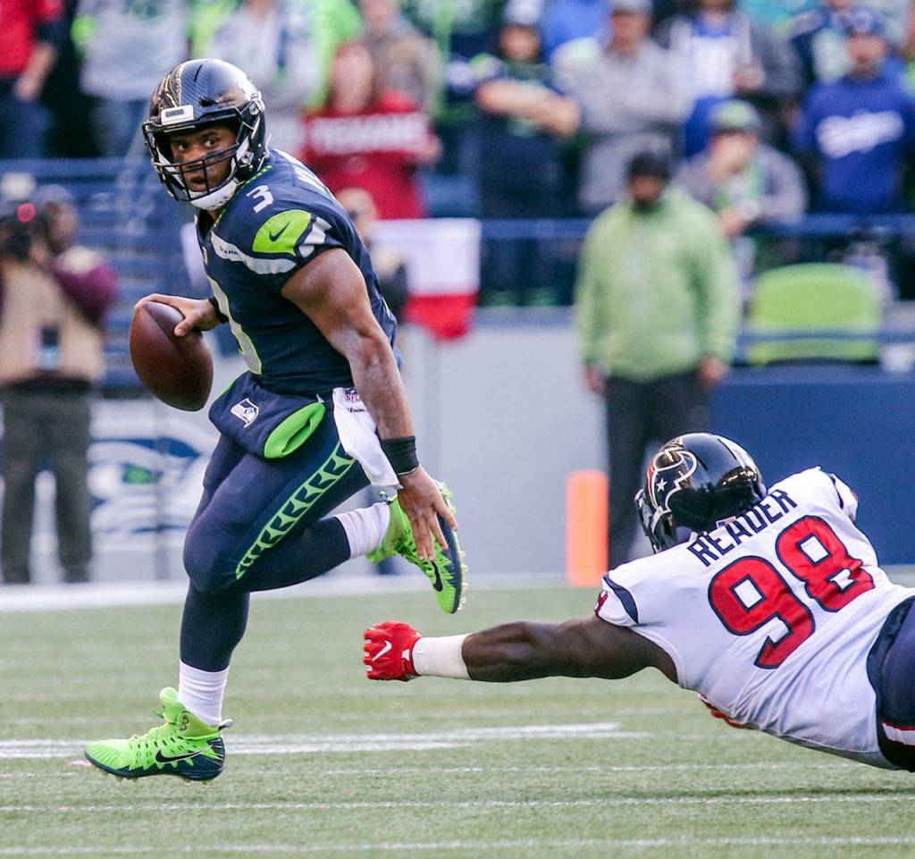 Seahawks quarterback Russell Wilson scrambles away from Texans D. J. Reader Sunday afternoon at CenturyLink Field on October 29, 2017`.(Kevin Clark / The Herald)
