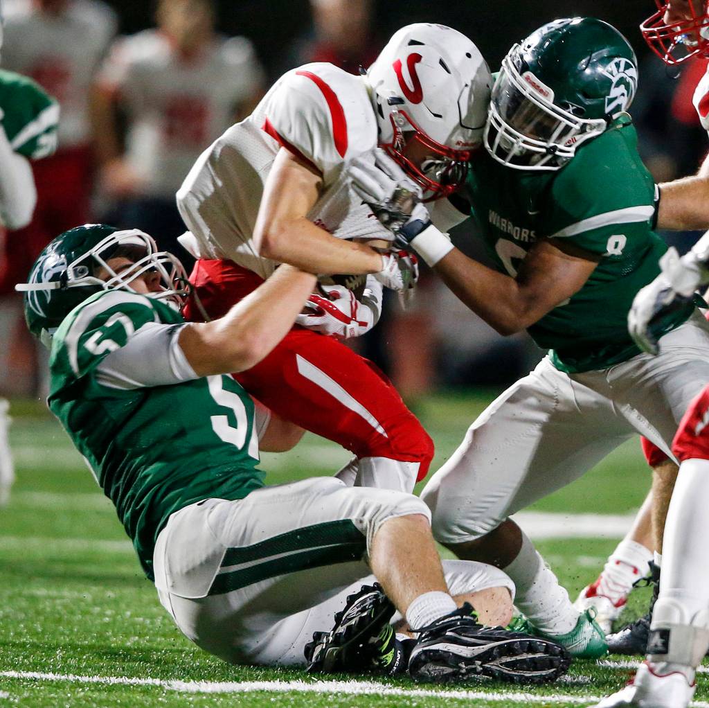 Snohomish Highs Tyler Massena (center) is brought down by Edmonds-Woodways Tyler McAtee (left) and Dominic Lawrence (right) during a game at Edmonds Stadium on Oct. 27. (Ian Terry / The Herald)