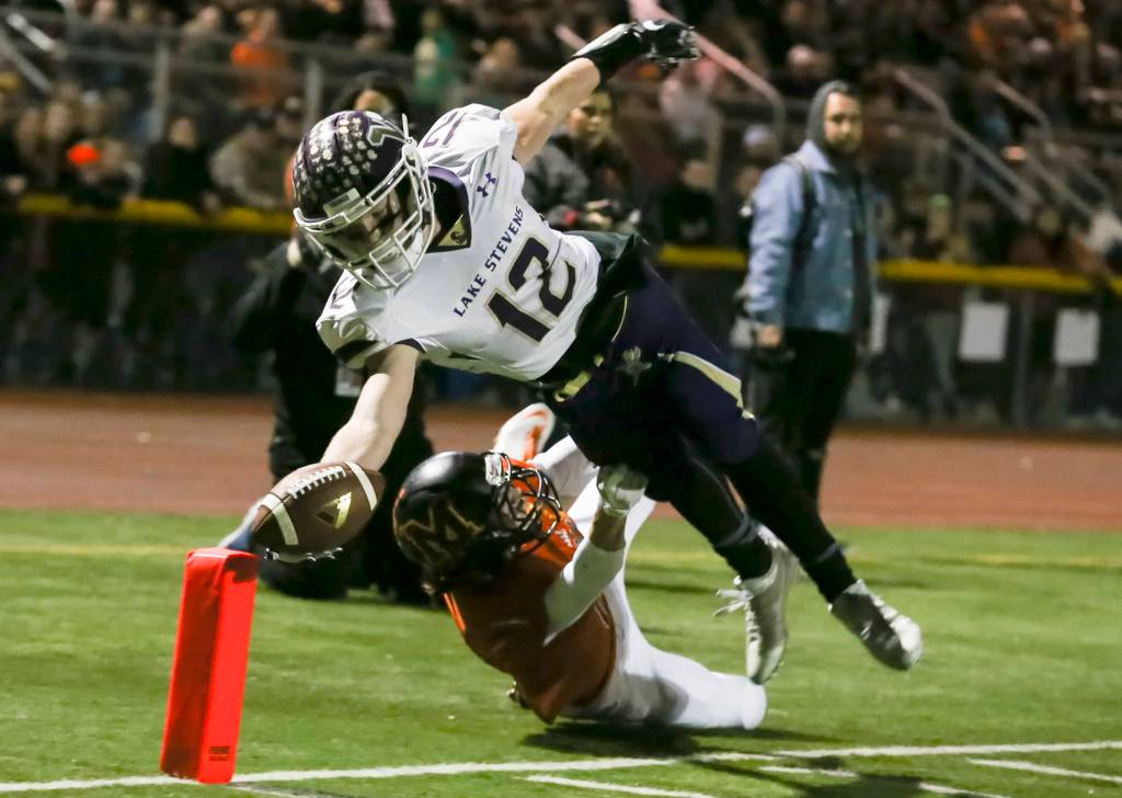 Lake Stevens Austin Murren dives for a touchdown with Monroes Skyler Barr trailing at Monroe High School in Monroe on Oct. 27. (Kevin Clark / The Herald)