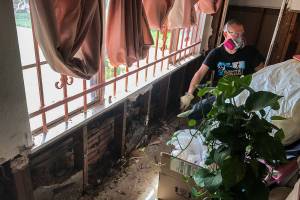 Kerry Day, 32, of Mill Creek, tears away drywall at a home on Guinevere Street in Houston, leaving the exterior brick exposed on both sides. (Photo courtesy of Greg Erickson)