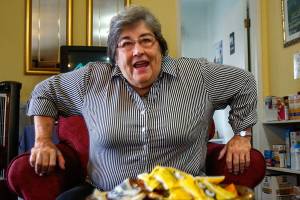 In the front room, known as the Welcome Room, Matthew House Executive Director Linda Paz jumps up from her chair to welcome volunteer Karol Bentley, who was arriving to help in the guest rooms and with family clothing and food supplies. (Dan Bates / The Herald)