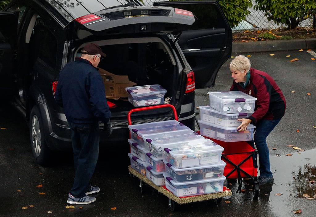 Assistance League volunteers David Gunderson (left) helps Happi Favro while she loads two carts with items to set up and sell at a holiday crafters marketplace being held upstairs in the leagues facilities on Evergreen Way in Everett. (Dan Bates / The Herald)