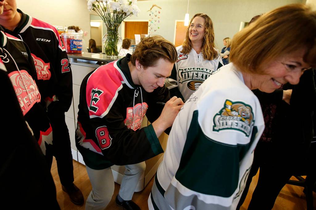 Silvertips left wing Brandson Hein (center) signs the back of a jersey for Providence Hospital RN Marcia Boffey during a team visit on Nov. 1, 2017. (Ian Terry / The Herald)