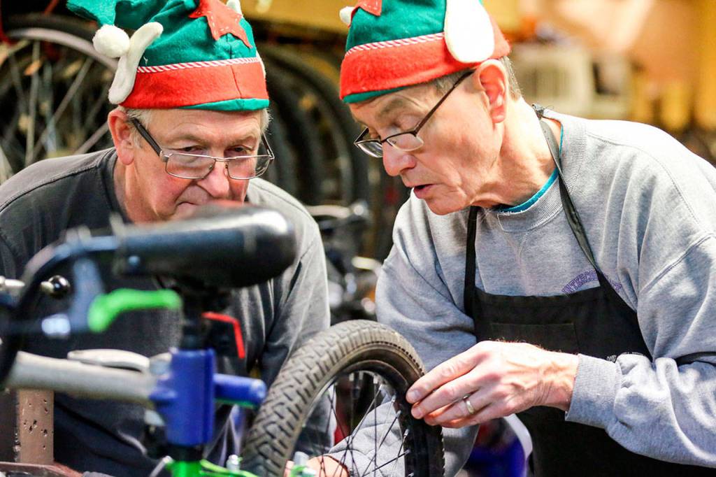 David Fox (left) and Larry Williamson look over a bicycle under repair at Sharing Wheels in Everett on Nov. 5. (Kevin Clark / The Herald)