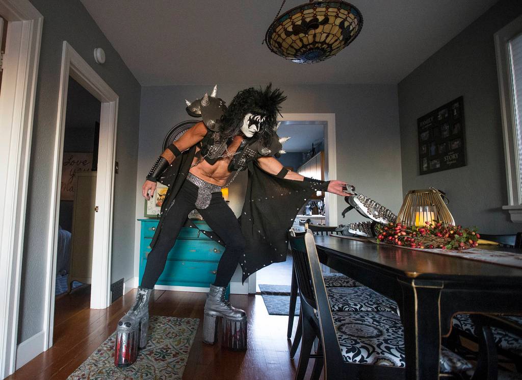 On platform shoes and standing seven feet tall, Everett paramedic Jack Murrin slowly stretches over to grab shin pads as he gets dressed up as Gene Simmons, of KISS fame, and heads out to a open mic at Cafe Zippy on Oct. 5 in Everett. (Andy Bronson / The Herald)