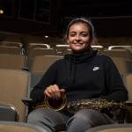 Lynnwood High School senior Venecia Lucio sits with her saxophone in schools theater Nov. 8. Lucio has led fundraisers as part of her work with Colores Unidos, which celebrates Latino and Spanish-speaking cultures. (Andy Bronson / The Herald)
