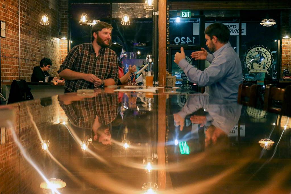 Colin Lothrop (left) talks with Sean Curran at Toggles Bottleshop in Everett on Nov. 8. (Kevin Clark / The Herald)