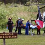 Rescue workers treat a survivor before she is airlifted, July 6, 2015, at the Big Four Ice Caves trailhead east of Verlot. Two other people died from injuries sustained in the collapse. Frontier Communications is considering removing a payphone at the Verlot ranger station, which could increase response time to similar emergencies. (Genna Martin / Herald file photo)