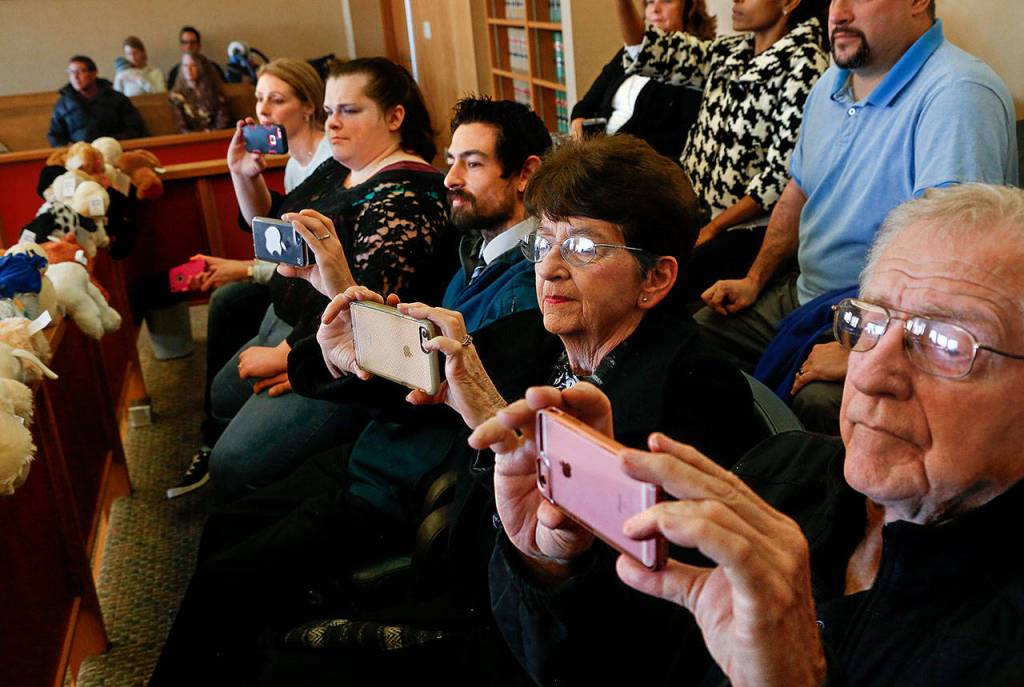 Taking aim with their cellphone cameras in the jury box, family members photograph the adoption proceedings of David and Kellie Preston with Sabrina, 7, and Savannah, 4. From right, foreground: great-grandfather and great-grandmother Dick and Billie Boggs, of Marysville, and Adrian and Kellsie Preston, of Everett. (Dan Bates / The Herald)