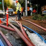 Water is pumped away from residential areas near the intersection of 136th Street SE and the Bothell-Everett Highway in Mill Creek on Wednesday. (Ian Terry / The Herald)