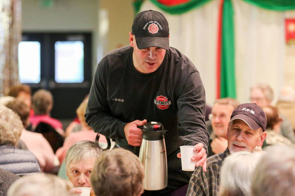 Jordan Evers distributes coffee Sunday afternoon during the annual community meal at Carl Gipson Senior Center in Everett. (Kevin Clark / The Herald)