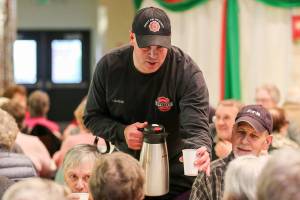 Jordan Evers distributes coffee Sunday afternoon during the annual community meal at Carl Gipson Senior Center in Everett on November 19, 2017. (Kevin Clark / The Herald)