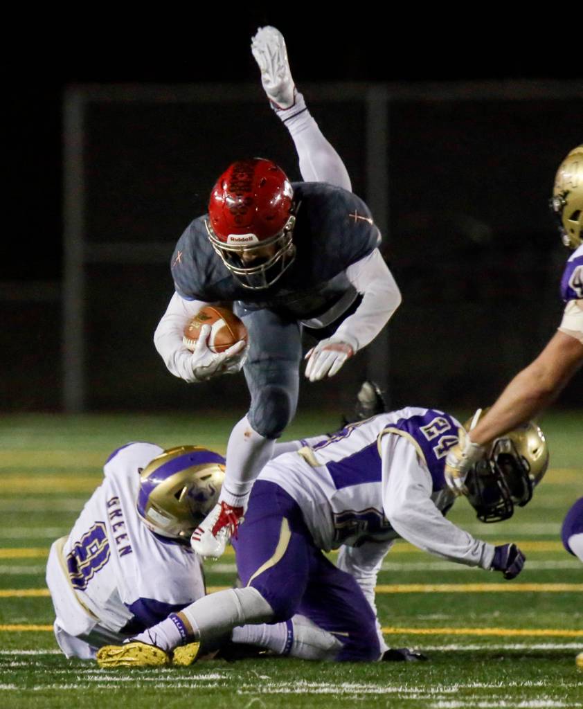 Archbishop Murphys Ray Pimentel jumps a tackle attempt by North Kitsaps Kyle Green (left) and Rily Solis at Veterans Memorial Stadium in Snohomish on Nov. 17. (Kevin Clark / The Herald)