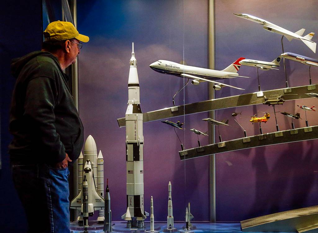 At the Future of Flight Aviation Center, a visitor pauses at a display case where a model of a British airways 747 (center) is exhibited next to models of rockets, spaceships and supersonic aircraft. (Dan Bates / The Herald)