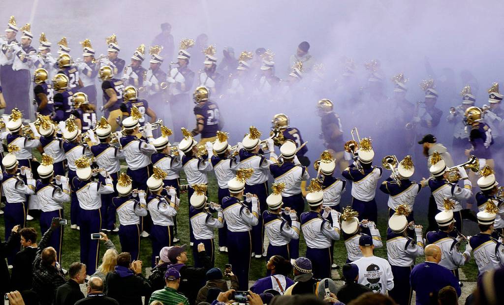The Husky band forms walls on either side of the tunnel for the players to run out on the field through as they make their appearance prior to the start of the game. Band members min also be dreaming of games when they could play in the sunshine. (Dan Bates / The Herald)